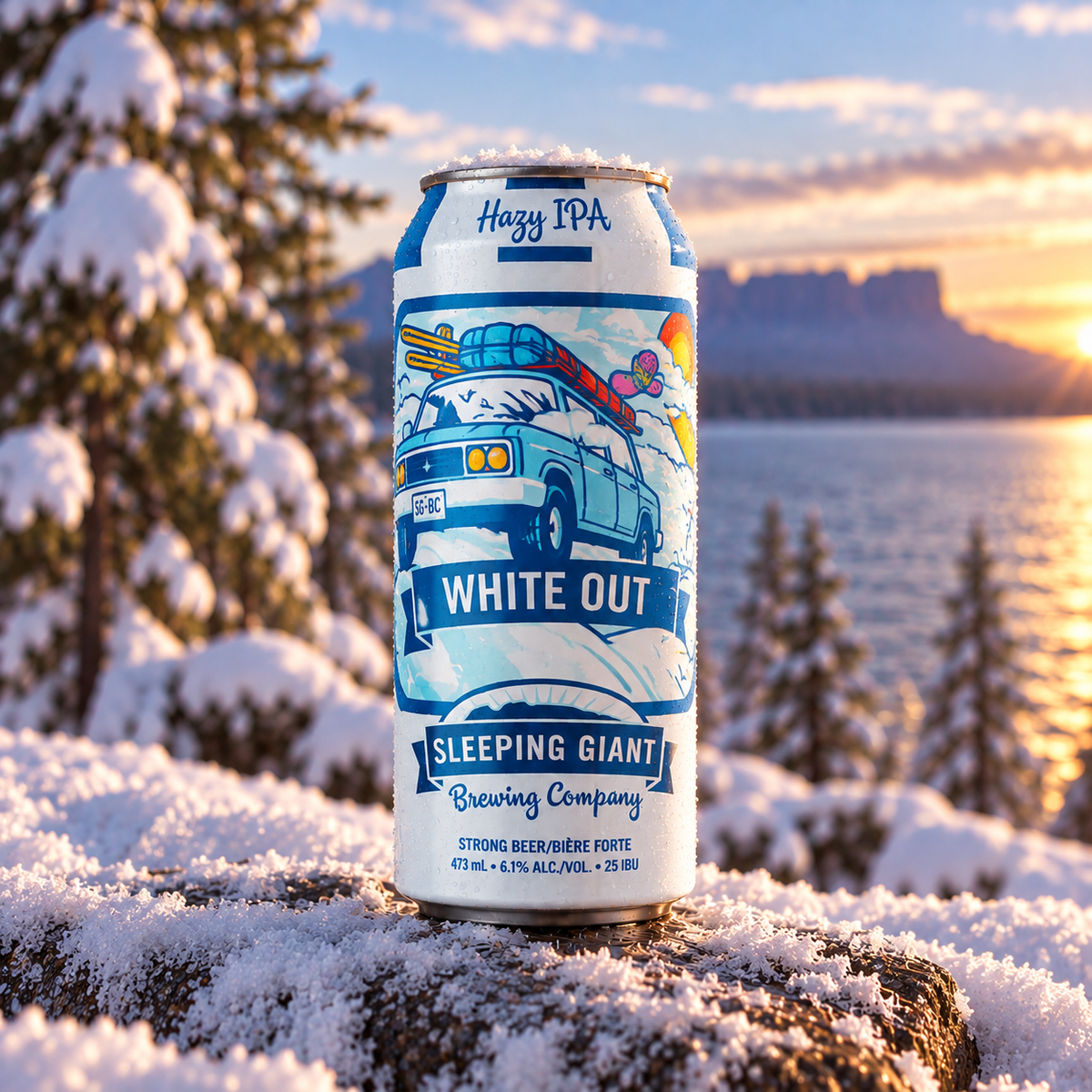 A can of Sleeping Giant Brewing Company 'White Out' Hazy IPA beer is shown standing on a snowy log outdoors by a lake at sunset, with snow-covered trees and distant cliffs in the background.